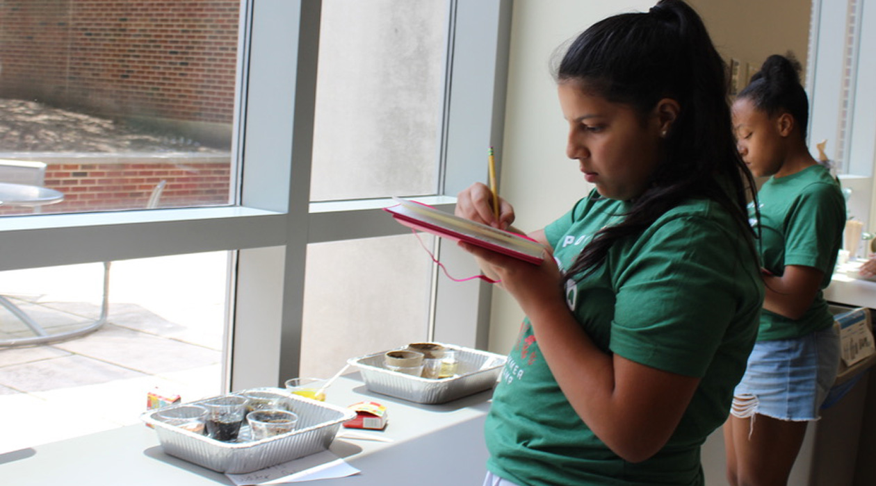 Campers take notes on their plant growth experiment results.